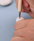 Hand using a tool from the Leather Craft Tools Kit With 20 Leather Stamping Tools, Leather Hammer, Swivel Knife, 5 Tracing Pens And 4 Tracing Papers.