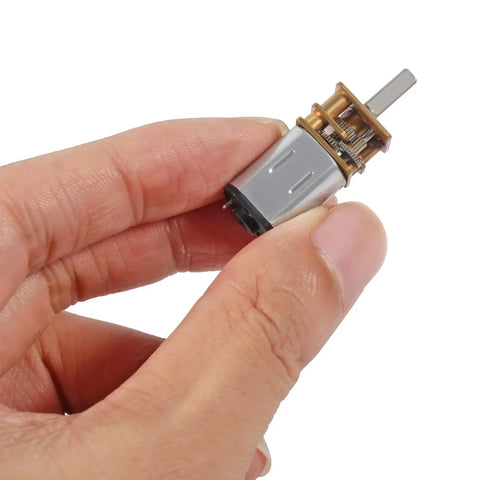 Hand holding a Beefy Four Pack 12V DC Gear Motor with All Metal Gearbox, showing compact size and visible gear mechanism