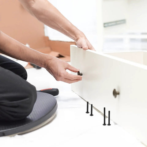 Person assembling furniture using Crib Hardware Replacement Kit Must Have 141 Piece Black Aluminum Alloy Bolts And Nuts Set.
