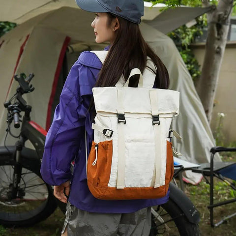 Rear view of a person wearing a Go To Lightweight Waterproof Backpack For Everyday Adventure, Large Capacity Daypack For Hiking Travel And Outdoor Camp Gear, Built Tough For Men And Women in a campsite setting.