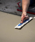 Person using White Lightning Hand Float For Concrete, 16 Inch Blade By 3 Inch, for smoothing concrete surface.