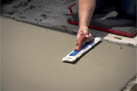 Person using White Lightning Hand Float For Concrete, 16 Inch Blade By 3 Inch, for smoothing concrete surface.