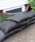 Grab And Go Flood Kit With 20 Water Activated Flood Bags In A Bucket For Fast Control of Flood Water stacked by a house entrance
