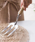 Hand holding Ergonomic Stainless Steel Hand Fork for Gardening, Rugged Cultivator Tool With Polished Finish, No Bend Grip.