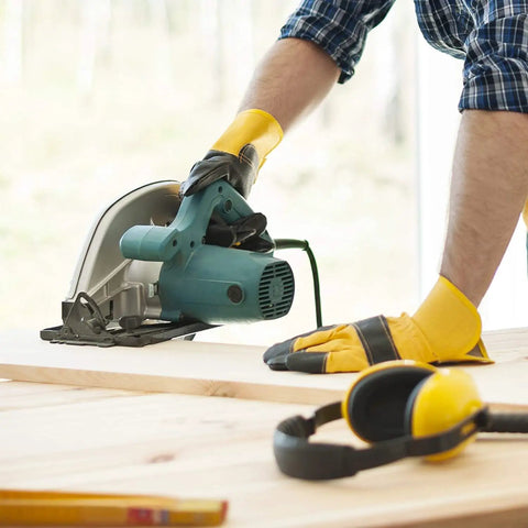 Person using a saw on a wooden board with protective gloves, related to Double Sided Woodworking Tape For CNC Templates And Pattern Routing.