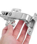 Hand holding stainless steel cabinet hinge from 4 pack concealed mounting hardware for corner doors with soft close dampers