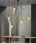 Sleek 12 Light Alabaster Pendant Lamp With Cylinder Shade And Killer Led Glow For Modern Dining Rooms pendant above a pink table.