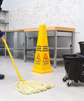 Person mopping commercial kitchen next to Omnifit Mop Bucket With Side Press Wringer And Soiled Water Insert 35 Quart Black Pro Grade