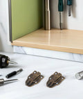 Retro Antique Duck Bill Toggle Latch 12 Pack With Hasp Catch For Jewelry Boxes And Suitcases on a work surface with tools.