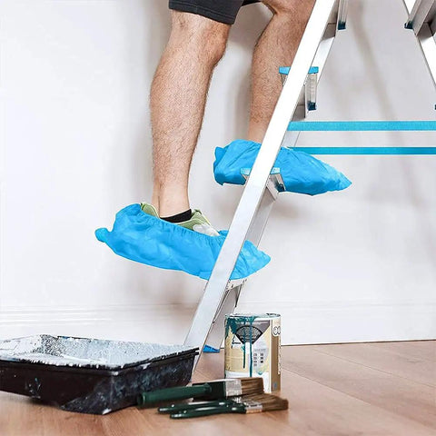 Person wearing blue 200 Packs Disposable Non Slip Shoe Covers Game Changer Thick Nonwoven Durable Booties on ladder during painting project