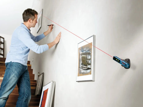 Man using Line And Point Laser Level With 65 Ft Range, Two Bubble Vials, Batteries Included, And Versatile Mount For Easy Setup