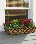 Adjustable Deck Railing Planter Boxes For Balcony Gardens Fits Railings From 2.1 To 6.3 Inches With Sturdy Metal Construction Ideal For Outdoor Plants On Deck Fence Or Porch Window Boxes Outdoor 24 Inch Long 4 Pack With Coco Coir Liner installed below a window holding red flowers and greenery.