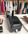 Heavy Duty Thermal Transfer Label Printer With Smooth 200 DPI Output And Zero Sweat Quiet Hustle Plug And Play Usb Lan Serial Port Setup For Wash Care Tags Jewelry Barcode Shipping Roll, viewed on a workstation.