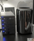 Top Shelf Five Bay Raid Hard Drive Enclosure Equipped With Dead Fast USB 3.0 Firewire 800 And Esata Ports Delivering Hella Reliable Throughput For Massive File Stacks In Sleek Black Frame on a desk with a black cylindrical device.