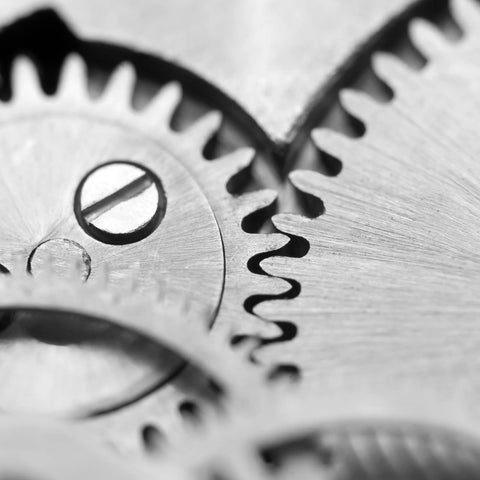 Close-up view of interlocking gears made from polished metal with a visible slotted screw head in the center.