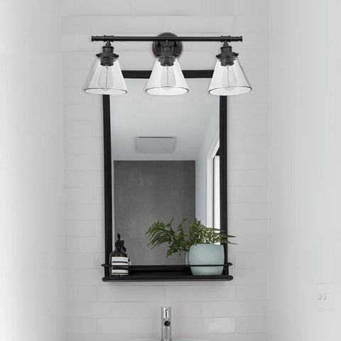 Three-Light Vanity Fixture In Oil Rubbed Bronze With Clear Glass Shades over mirror in modern bathroom setting