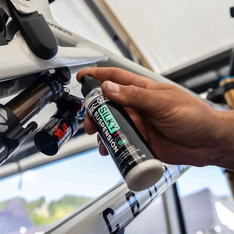 Hand applying Silky Suspension Serum 100ml Protective Spray For Bike Shocks And Seals Reduces Stiction And Friction Repels Dirt