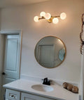 Five Light Bathroom Vanity Light Fixture With Milk Glass Globes In Brass Finish Mounted Above Round Mirror with Sink