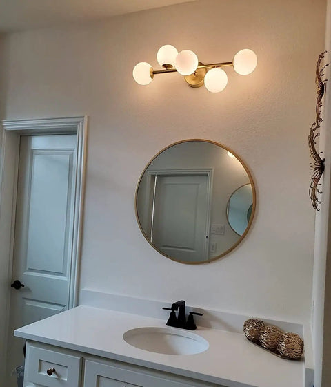 Five Light Bathroom Vanity Light Fixture With Milk Glass Globes In Brass Finish Mounted Above Round Mirror with Sink