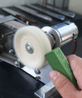 Hand using Dope Green Polishing Compound For Sharpening And Buffing Ultrafine Aluminum Oxide And Chromium Oxide Blend 1 To 2 Micron Particles Delivers 10000 To 14000 Grit Edge 2 Pack on a rotating tool to sharpen a blade