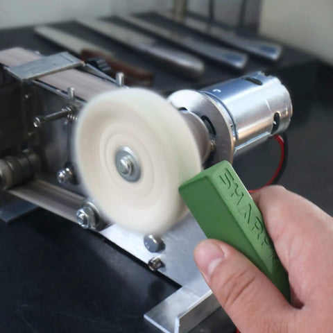 Hand using Dope Green Polishing Compound For Sharpening And Buffing Ultrafine Aluminum Oxide And Chromium Oxide Blend 1 To 2 Micron Particles Delivers 10000 To 14000 Grit Edge 2 Pack on a rotating tool to sharpen a blade