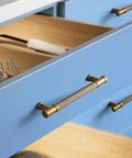 Close-up of Six Pack Knurled Cabinet Pulls Antique Brass Drawer Handles 5.04 Inch on blue kitchen drawers.
