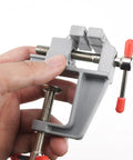 Hand holding Mini Jeweler Table Clamp For Jewelry Making And Electronics Craft Projects Portable Bench Vise in gray aluminum