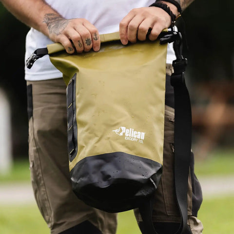 Person holding ExoDry 30L Large Drybag Waterproof with Roll Top Closure and Backpack Style Straps in an outdoor setting.