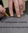 Close-up of a hand tracing a gasket outline on HTJZWG non-asbestos gasket sheet (dark gray)