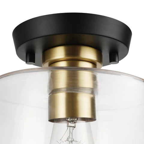 Close-up of Polly 1 Light Flush Mount Ceiling Light with black finish, clear glass shade, antique brass socket, vintage Edison bulb.