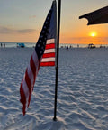 Beach scene with American flag on heavy duty ground stakes torch stand for outdoor tiki torches at sunset.