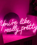 You Are Really Pretty Pink Led Neon Sign For Indoor Bedroom Decor Wall Art Backdrop 25.5x11.8 Inches Flexible Silicone Neon Light For Chill Vibe Parties Weddings Living Room, lit in a romantic glow on a shelf against a dark background.