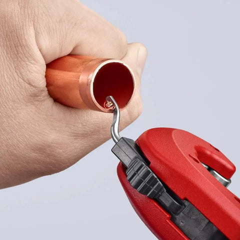 Close-up of TubiX Pipe Cutter With Quick Adjustment One Hand No Fuss Quick Lock cutting a copper pipe held by a hand.