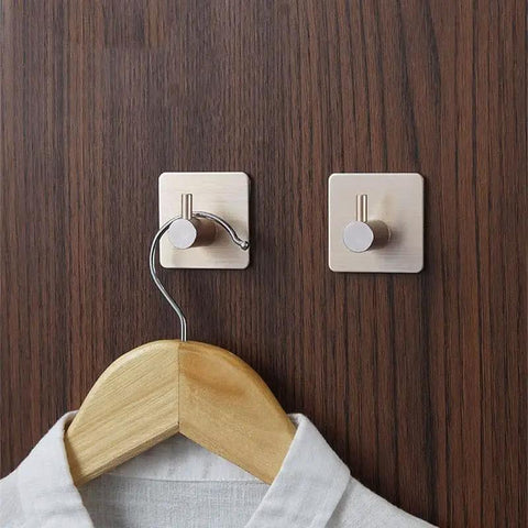 Built Tough Aluminum Self Adhesive Wall Hook Grips Tight Without Drilling Knockout Black robe hanger holding a wooden hanger on a wall.