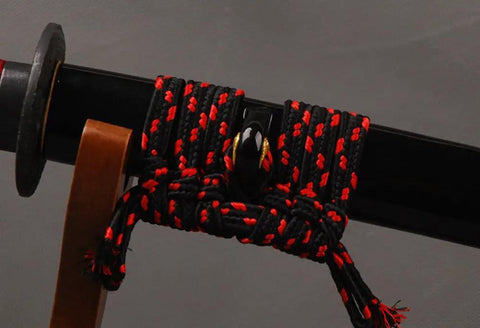 Close-up of a katana scabbard with black and red rope, showcasing 3.3 Yard Synthetic Silk Sageo Wrapping Cord For Katana Scabbard DIY Maintenance TopNotch Black High Quality Japanese Samurai Sword Saya Cord For Easy Wrapping And DIY Sword Care.