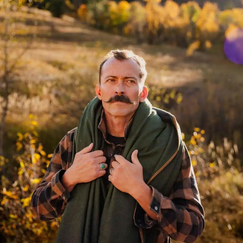Man wearing Beefy Warmth And Rugged Durability Military Wool Blanket For Outdoors Camping Picnics Travel Stadium Events and Survival Kits Washable Heavyweight Olive Green in nature