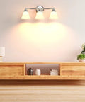 Dope Three Light Chrome Vanity Light Fixture With Frosted Glass Shades, mounted above wooden console in living room.
