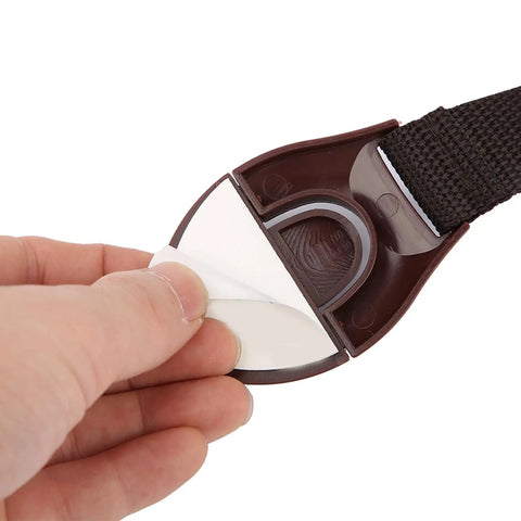 Hand holding Baby Safety Locks For Cabinets And Drawers Adhesive Child Proofing Locks with brown ABS part and nylon belt.