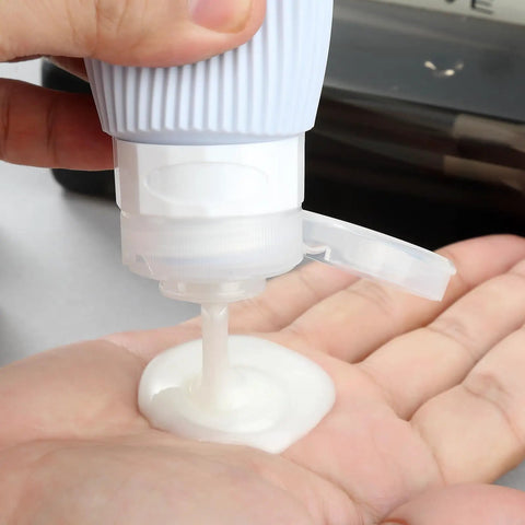 Person dispensing liquid from TSA Approved Travel Bottle Set With Leak Proof Silicone Squeezable Containers for Toiletries.