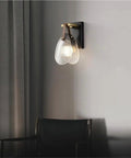 Fluted Glass Wall Sconce Ribbed Shade Leather Strap Brass Finish Metal Light 10 Inch Height mounted on wall beside chair.