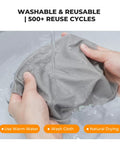 Front view: gray microfiber lens cleaning cloth being wrung under running water.
