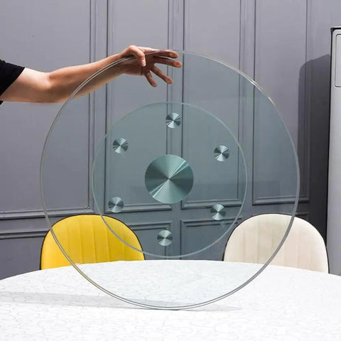 Top Shelf Thick Tempered Glass Lazy Susan Rotating Serving Tray Easy Peasy Clean Spinner held above a dining table.