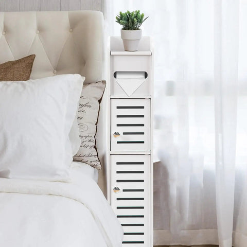 Slim Over Toilet Storage Cabinet For Small Bathrooms beside bed, narrow white floor organizer with two doors and potted plant.