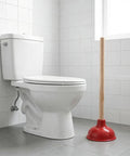 Eighteen Inch Heavy Duty Toilet Plunger Featuring A Thick Red Rubber Cup And Sturdy Wood Grip ready next to white toilet in bathroom.