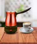 Electric Turkish Coffee Pot Kettle With Cool Touch Handle And Stainless Steel Body Travel Size 0.3L Red next to a coffee cup.