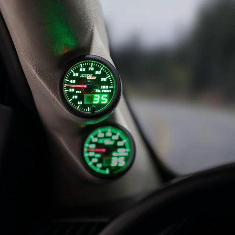 MaxTow 100 PSI oil pressure gauge kit with black face and green LED dial installed on a truck dashboard (2-1/16 in / 52 mm)
