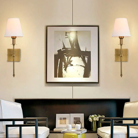 Two Pack Brushed Brass Wall Sconces With Fabric Shade in living room setting, wall mounted beside artwork, gold finish.
