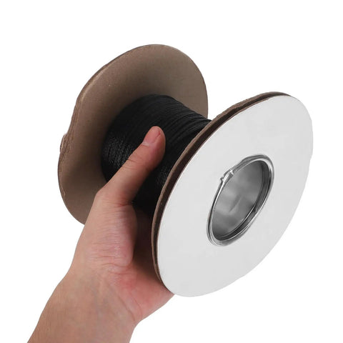Hand holding a spool of black Flame Retardant Braided Cable Sleeve Expandable Mesh Wire Loom Cord Protector for cable management.