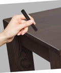 Hand using 2 Pack Wood Filler Sticks for Furniture Repair Scratch Remover Pens Quick Fix Paint Markers on dark wood table corner
