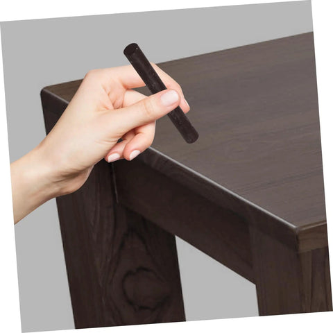 Hand using 2 Pack Wood Filler Sticks for Furniture Repair Scratch Remover Pens Quick Fix Paint Markers on dark wood table corner